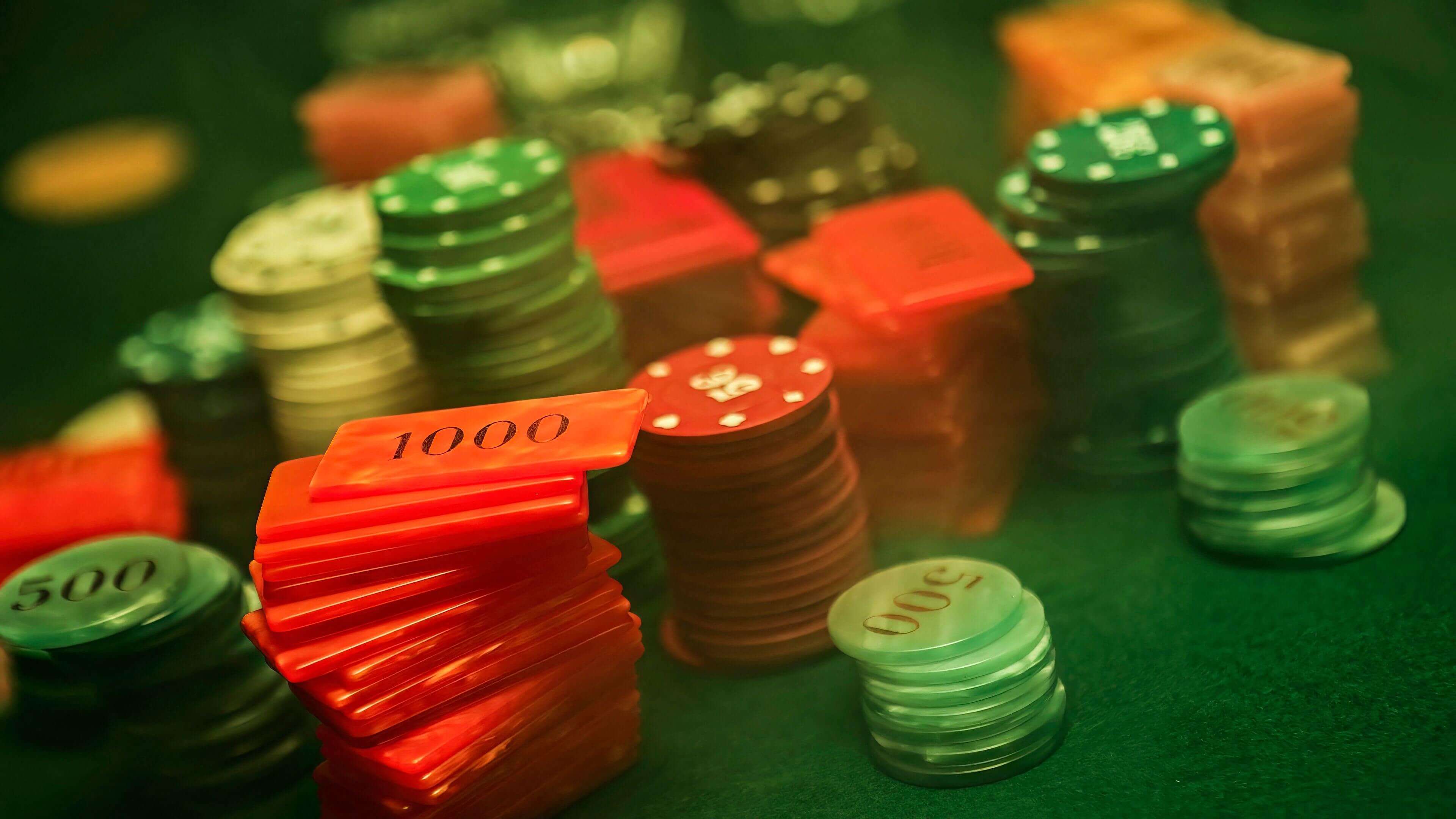 Colorful casino poker chips and red 1000-value plaques stacked on a green felt table