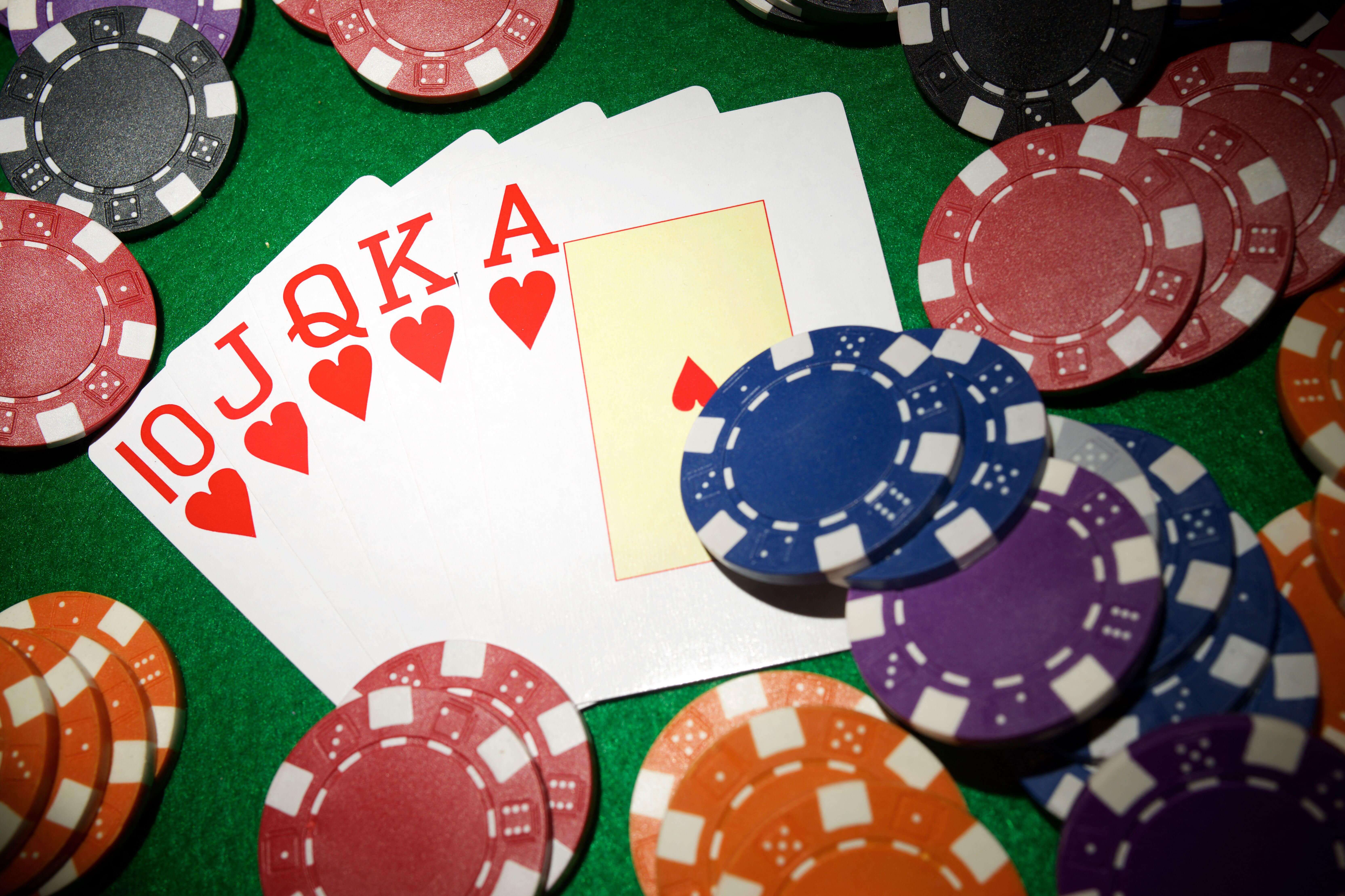 Royal flush in hearts with colorful poker chips on a green casino table